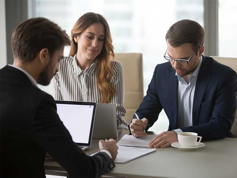 Couple signing lease agreement with car dealer at a desk